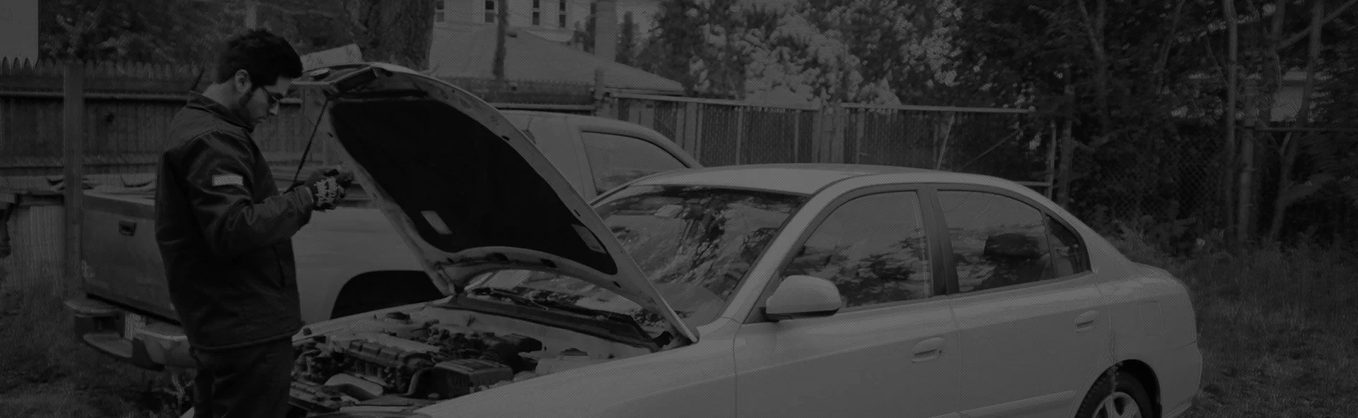 Image of a mechanic looking under the bonet of a car, ready to do auto repairs