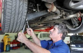 Image of a mechanic checking the tightness of a bolt on the suspension, underneath a car during a logbook service
